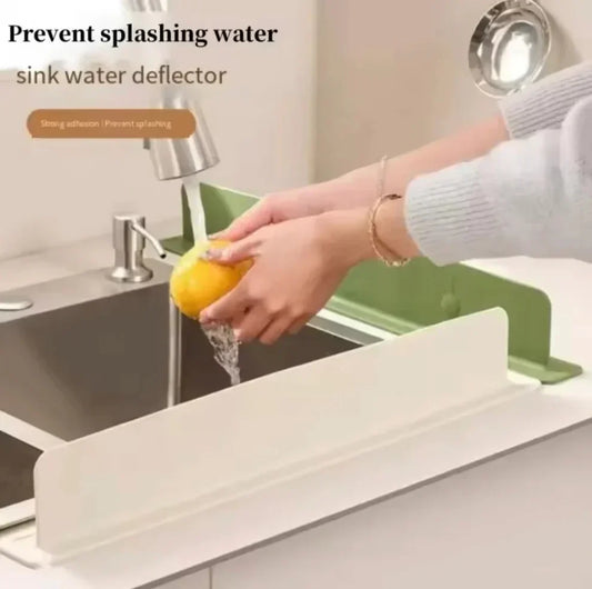 Person washing a lemon over a sink water splash guard deflector, designed to prevent splashing water, keep countertops dry, and improve cleanliness around the kitchen sink.