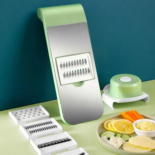 Multifunctional kitchen slicer with interchangeable blades displayed on a green surface. Features a versatile food preparation tool designed for slicing, chopping, shredding, and cutting vegetables and fruits quickly and efficiently, making meal preparation easier and more convenient.