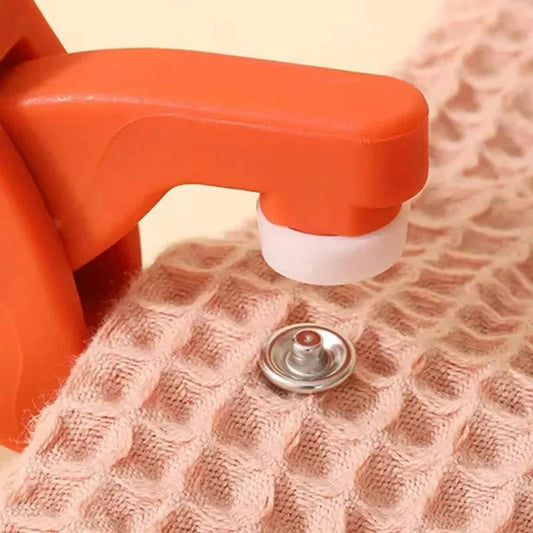 Close-up of an orange chair armrest applying pressure to a textured pink surface with a metal snap button, demonstrating a durable furniture protection pad designed to prevent scratches and reduce wear on floors and surfaces.