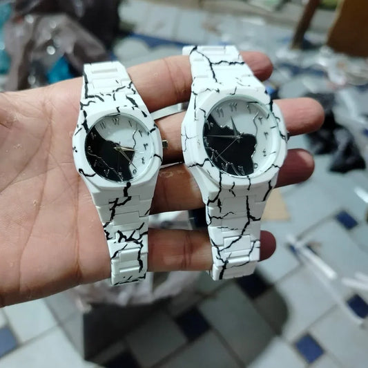 Close-up of a matching white marble couple wrist watch set with black marble pattern, featuring men's and women's watches with elegant round dials and white straps.