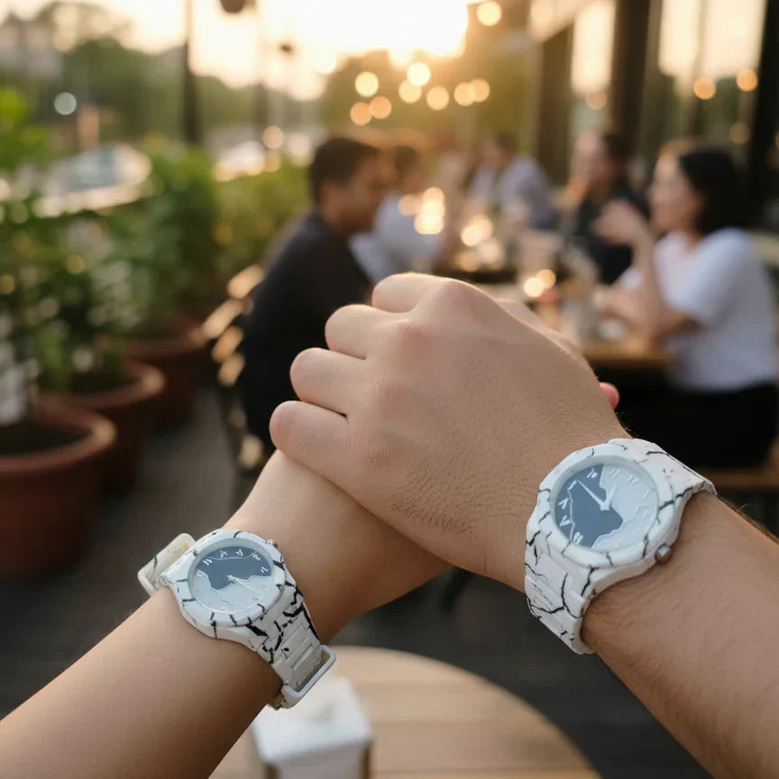 Couple wearing matching white marble pattern wrist watches with white straps while holding hands at an outdoor café during sunset, showcasing a stylish his and hers watch set.