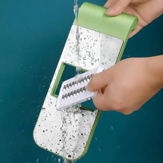 Person cleaning a green and white slotted turner with running water against a teal background. Demonstrates an easy-to-clean kitchen utensil designed for cooking, serving, and food preparation, featuring a durable and hygienic design for everyday kitchen use.