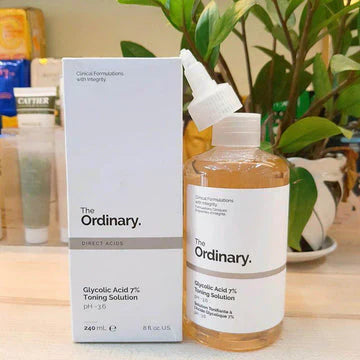 The Ordinary Glycolic Acid 7% Toning Solution displayed on a wooden surface with a green plant in the background, highlighting a gentle exfoliating toner designed to improve skin texture, brightness, and overall radiance.